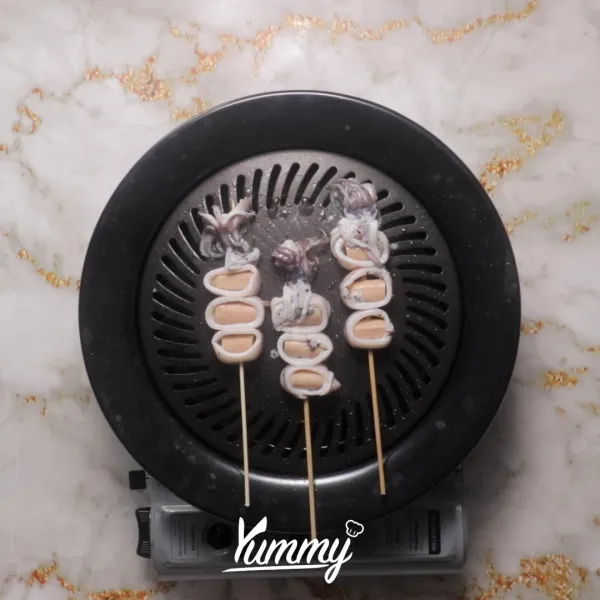Panasi pan/grill dan olesi dengan minyak zaitun, lalu bakar sate cumi. Olesi dengan campuran saus. Balik kedua sisi sesekali dan olesi hingga bumbu meresap. Masak selama 7 menit.