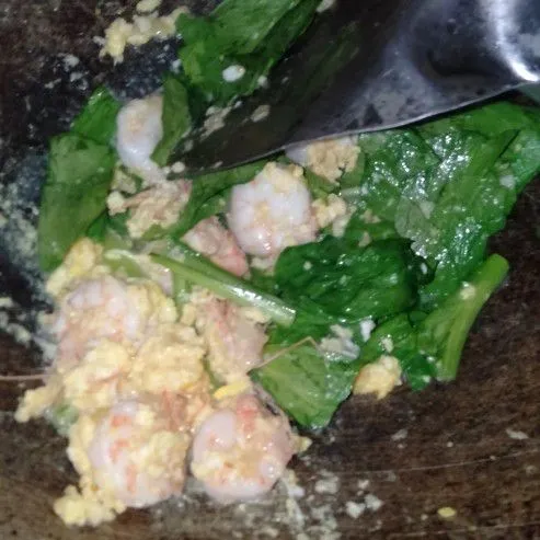 Setelah harum, masukan telur kemudian orak-arik dan masukan udang serta sawi hijau, tumis hingga layu.