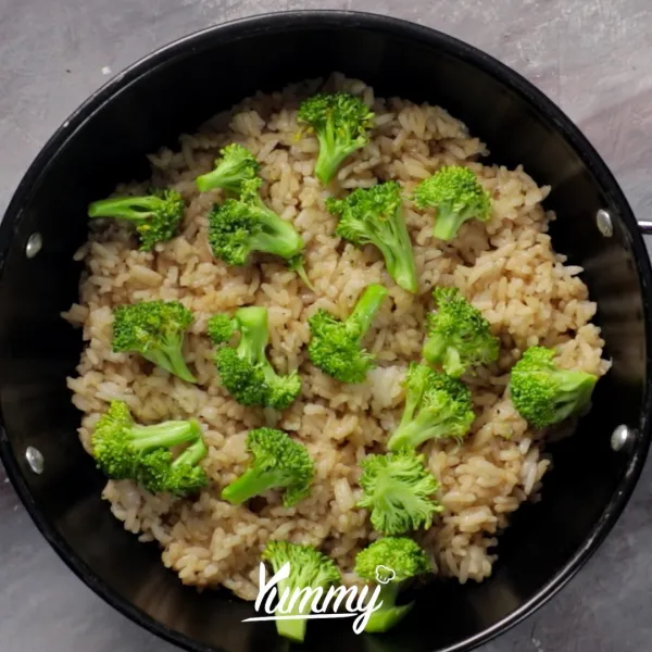 Tuang nasi ke dalam cetakan tahan panas, tuang brokoli dan susun jamur diatasnya.