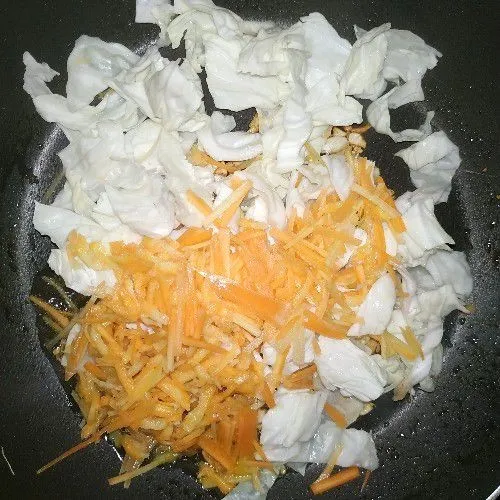 Masukkan lada bubuk, garam, dan kaldu bubuk kemudian tambahkan wortel dan sayur kol. Aduk dan masak hingga sayur kol layu
