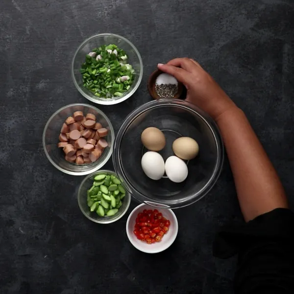Tuang telur ke dalam mangkuk besar. Campurkan dengan bawang daun, sosis, cabai rawit, petai, garam, lada hitam. Aduk hingga merata.