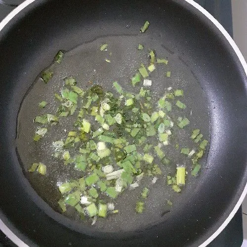 Panaskan minyak goreng lalu tumis daun bawang hingga setengah matang.