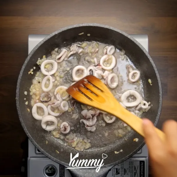 Panaskan minyak, tumis bawang bombay dan bawang putih hingga wangi. Masukkan cumi. Masak hingga cumi matang.