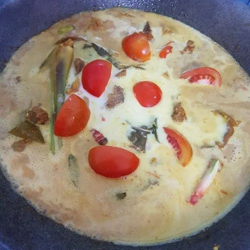 Tuang santan kental dan masukkan tomat serta garam, gula, dan kaldu bubuk, lalu koreksi rasa dan angkat setelah matang dan semua bumbu merasuk.