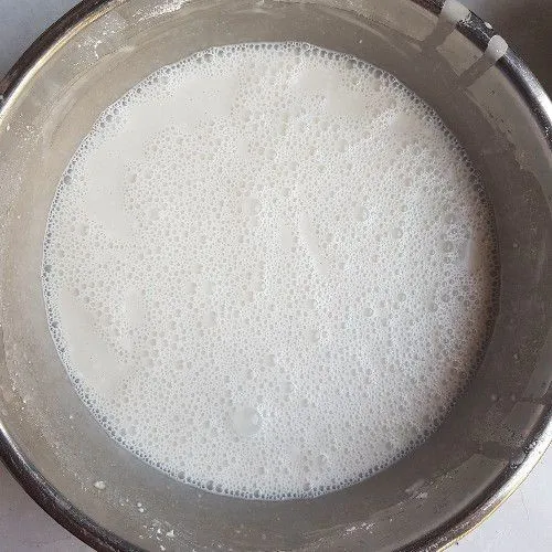 Kemudian tuang santan matang ke dalam campuran tepung secara bertahap sambil diaduk hingga adonan licin.