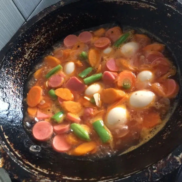 Masukkan wortel terlebih dulu karena wortel lama matangnya. Selanjutnya masukkan buncis, sosis, dan telur puyuh.