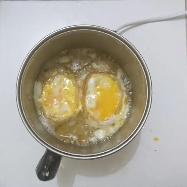 Tuangkan telur ke dalam bawang yang sedang digoreng.