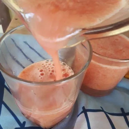 Tuangkan jus tomat dalam gelas di atas sari jeruk.