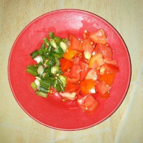 Potong-potong daun bawang dan tomat.