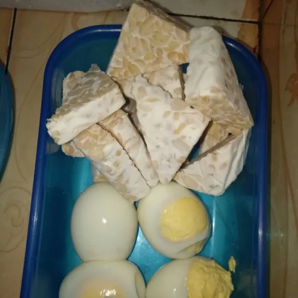 Rebus telur lalu kupas. Potong tempe lalu sisihkan.