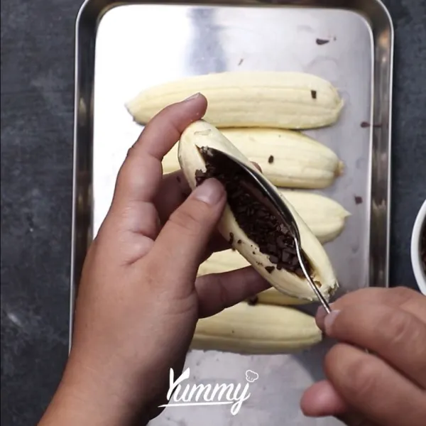 Belah pisang di bagian tengah jangan sampai terputus. Masukkan coklat di dalam  nya. Tekan pisang agar bagian lubang tertutup.