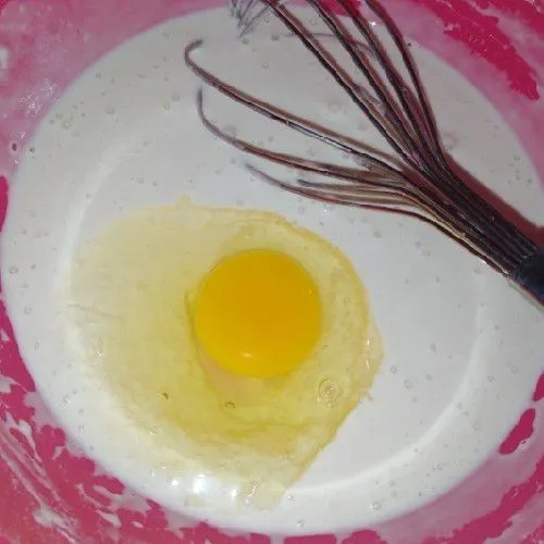 Masukkan santan sedikit demi sedikit. Aduk menggunakan whisk sampai kalis tidak bergerindil. Kemudian masukkan telur, minyak goreng dan pasta strawberry, aduk rata. Diamkan 30 menit.