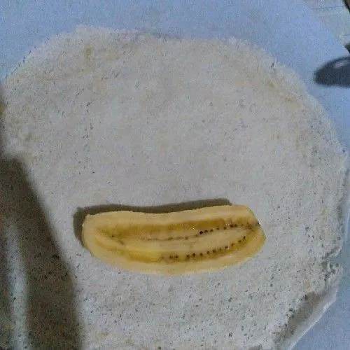 Letakkan pisang diatas kulit lumpia, lalu taburi 1/2 sdm coklat powder ke atas pisang.