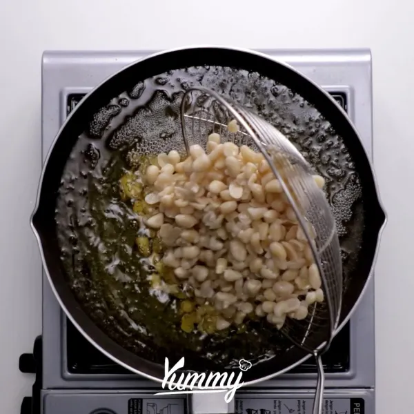 Goreng kacang dalam minyak panas dengan api sedang. Masukkan bawang putih iris dan daun jeruk ketika kacang sudah tidak bewarna putih.
