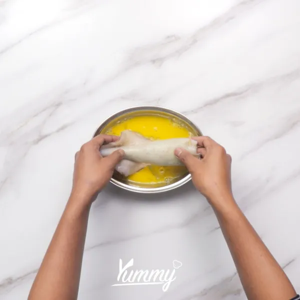 Balurkan cumi yang sudah terisi dengan nasi ke dalam kocokan telur. Lalu angkat.