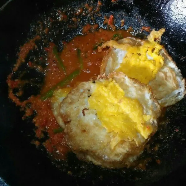 Tambahkan garam dan penyedap rasa, lalu masukkan telur ceplok ke dalam wajan.