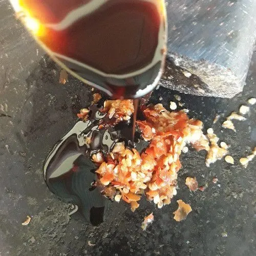 Ulek cabai rawit, bawang putih, dan garam. Tambahkan kecap manis. Aduk sampai tercampur rata.
