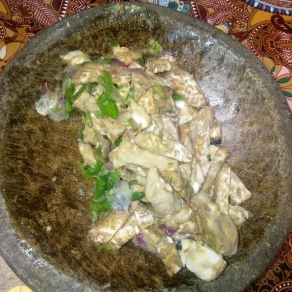 Tekan-tekan sedikit tempe ke dalam cobek bumbu yang digiling.