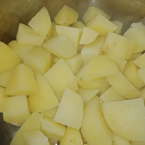 Kupas kentang dan potong dadu agar masak lebih cepat merata, lalu direbus.