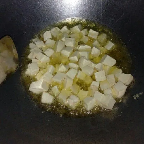 Potong tahu kecil-kecil, kemudian goreng sampai warna kecokelatan, kemudian angkat, dan tiriskan.