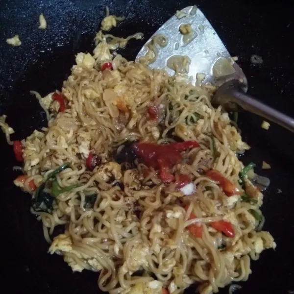 Matikan kompornya, kemudian masukkan bumbu mie instan, saos, kecap dan minyak mie instan.