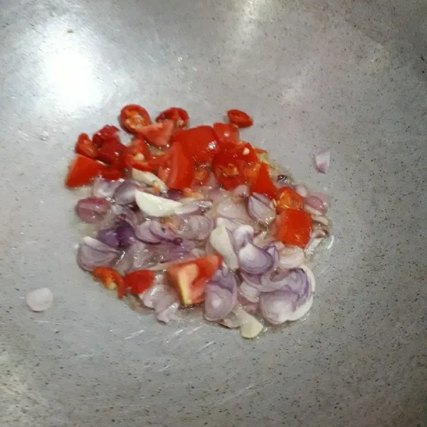 Masukkan bawang merah, bawang putih, cabai rawit, dan tomat. Tumis sampai harum dan layu.