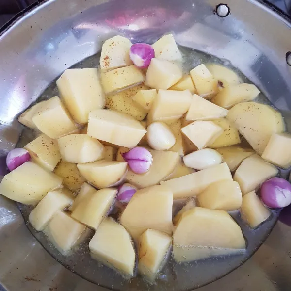 Panaskan secukupnya minyak kemudian goreng hingga matang kentang, bawang merah, dan bawang putih.