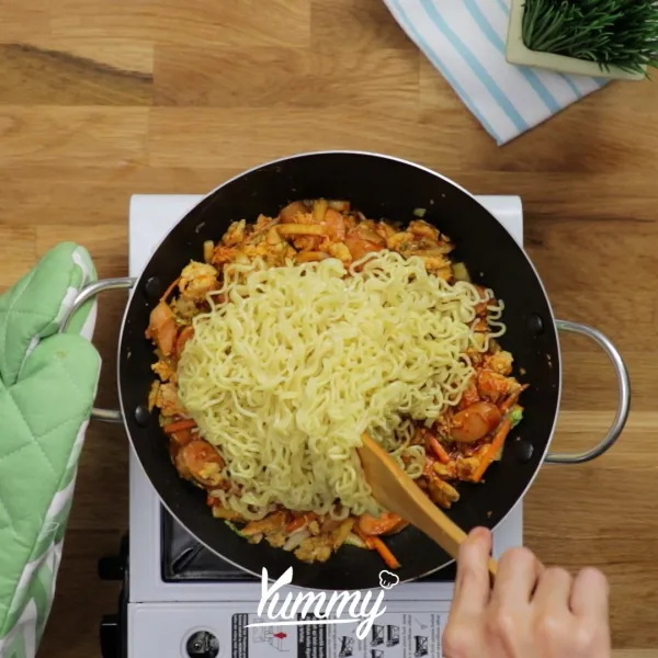 Masukkan mie instan yang sudah direbus ½ matang, kemudian aduk rata. Koreksi rasa. Sajikan Suki Mie Instan Goreng ala Yummy dengan taburan bahan pelengkap sesuai selera dan topping telur mata sapi ½ matang.