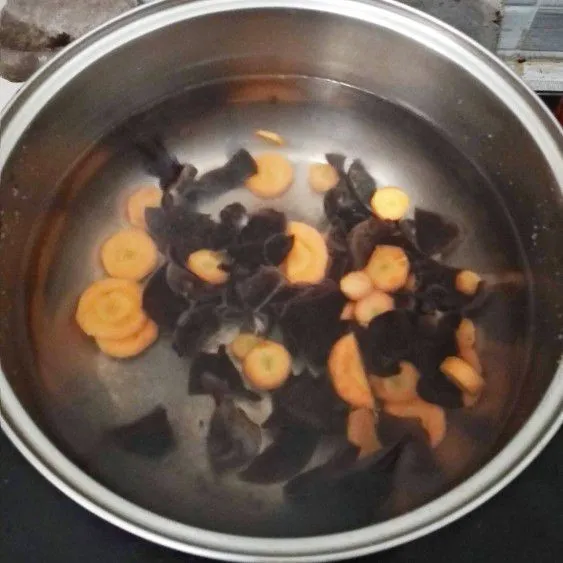 Masak air untuk kuah sop hingga mendidih. Masukkan jamur kuping dan wortel lalu masak hingga mendidih.