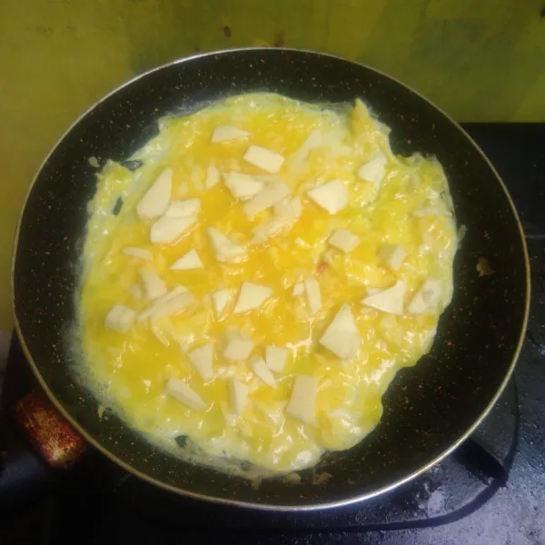 Saat telur bagian atas sudah terlihat tidak terlalu creamy, atau sesaat sebelum matang, tambahkan keju diatasnya. Kemudian lipat telur menjadi separuh lingkatan teflon, masak sebentar sambil di balik. Angkat dan matikan api, siap disajikan.