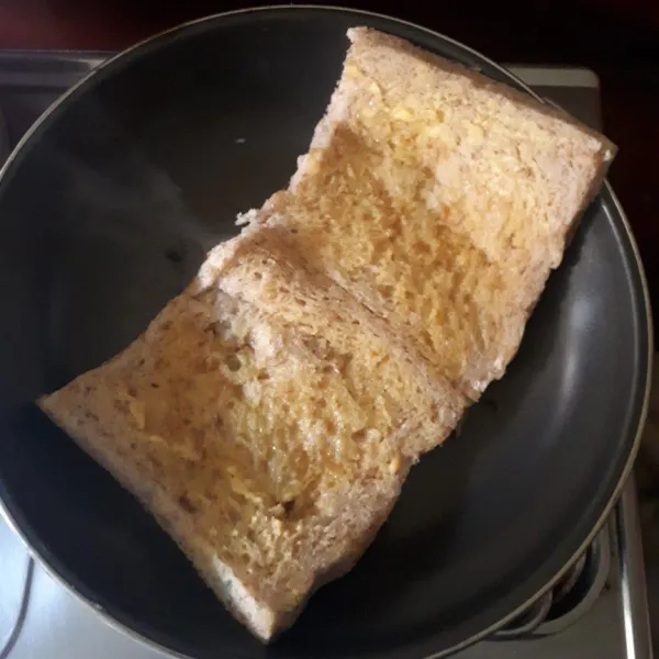 Olesi roti gandum di kedua sisi dengan margarin.