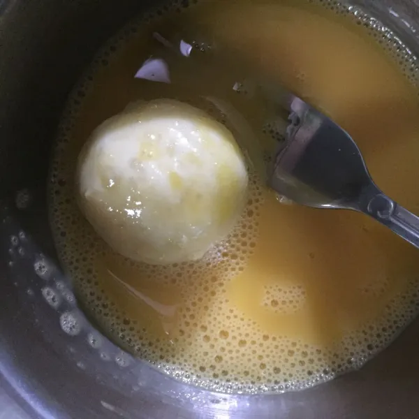 Celupkan bola-bola singkong ke dalam telur yang telah dikocok lepas.