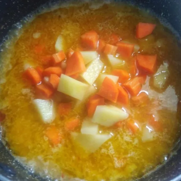 Tambahkan kentang dan wortel, masak hingga setengah empuk.