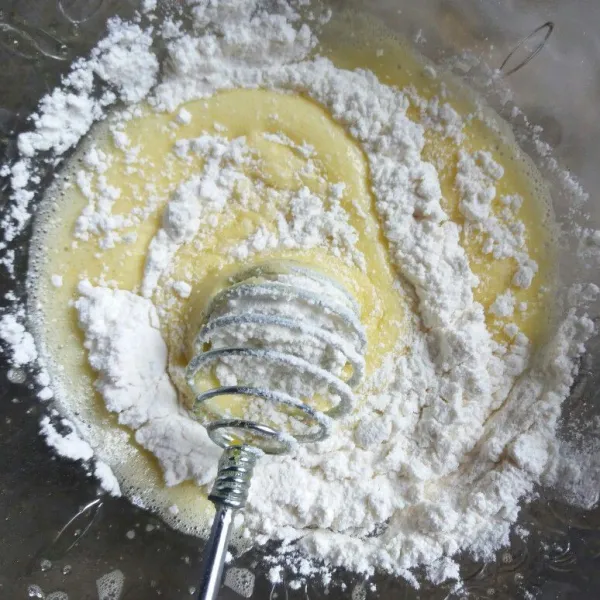 Masukkan tepung ke adonan telur yang sudah dikocok sedikit-sedikit. Aduk merata pelan-pelan.
