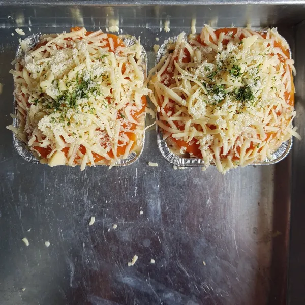 Panaskan oven. Selagi memanaskan oven, masukkan campuran spaghetti ke dalam wadah aluminium foil / loyang. Kemudian oles permukaan spaghetti dengan saus tomat, tambahkan keju parut, parsley flakes,dan parmesan. Lakukan hal yang sama hingga habis. Setelah itu panggang spaghetti selama 25 menit di suhu 150°C. Setelah matang keluarkan dari oven, dan spaghetti siap disajikan.