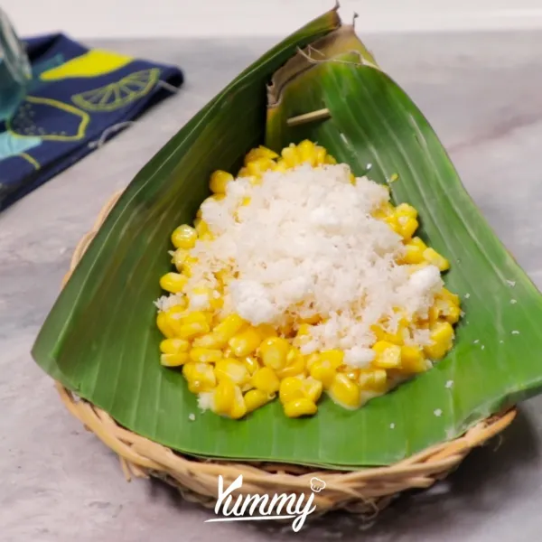 Siapkan daun pisang pincuk lalu isi dengan jagung lalu tambahkan kelapa parut kukus di atasnya.