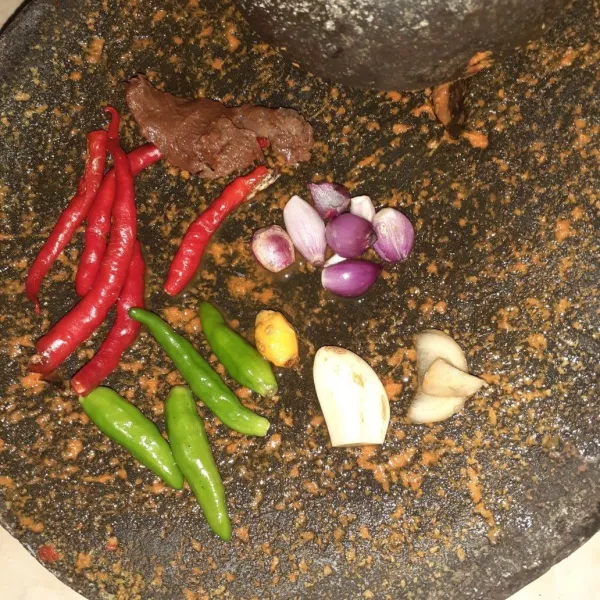 Giling bumbu halus, bawang merah, bawang putih, jahe, kunyit, cabai merah, cabai rawit, dan asam sunti.