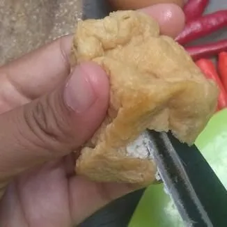 Kerat tahu dengan pisau agar berlubang.