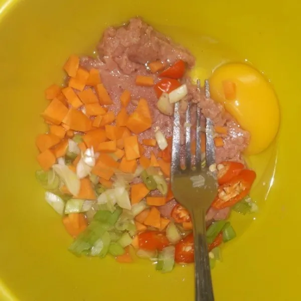 Masukkan telur ke mangkuk, kemudian masukkan irisan cabai, daun bawang, potongan dadu wortel, dan kornet.