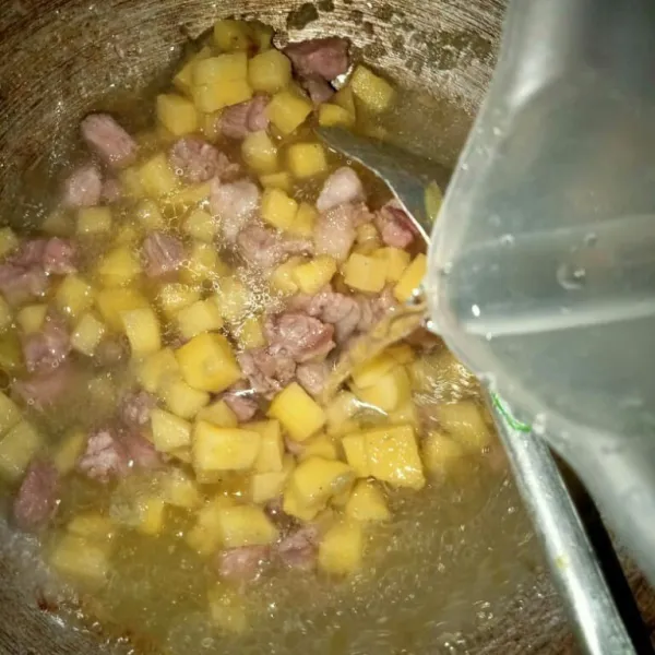 Masukkan kentang dan daging beserta air, lalu aduk rata, tambahkan garam, kaldu bubuk, dan gula.