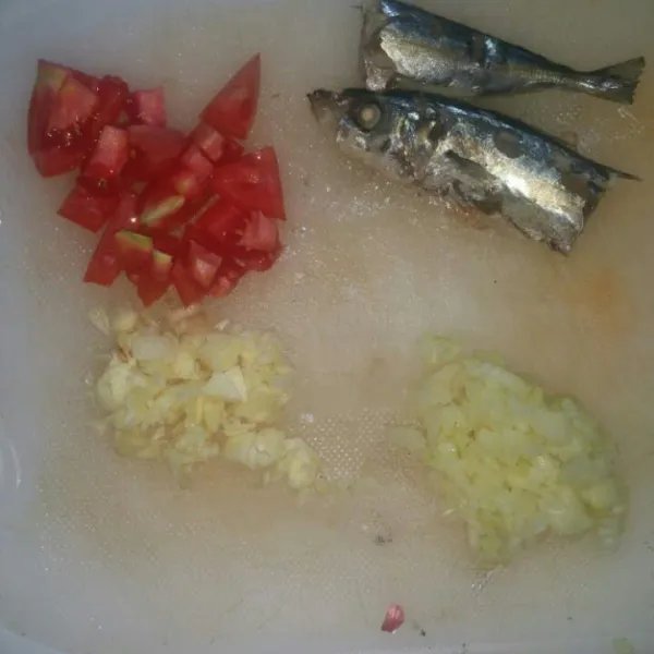 Bersihkan ikan, potong menjadi beberapa bagian. Cincang halus bawang putih dan bawang bombay, potong dadu tomat.