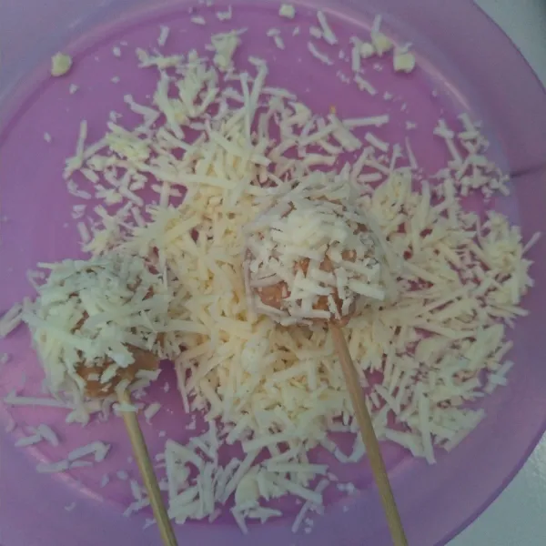 Taburi atau gulingkan adonan ke dalam keju, lakukan sampai adonan biskuit habis.