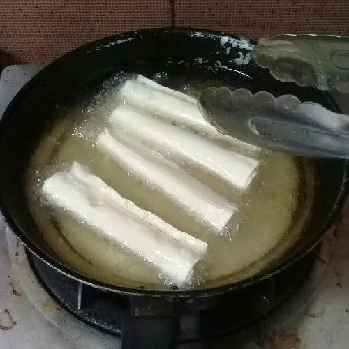 Goreng spring roll dalam minyak panas.