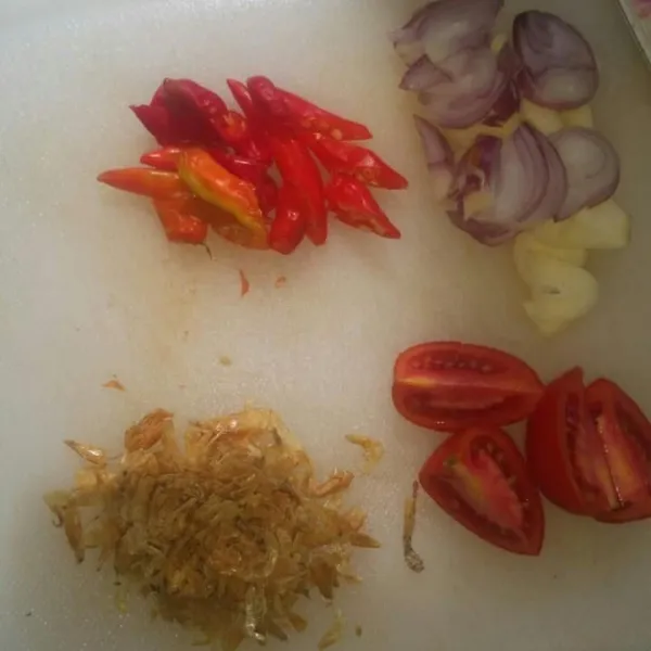Potong-potong bawang merah, bawang putih, cabe rawit, tomat, dan siapkan ebi.