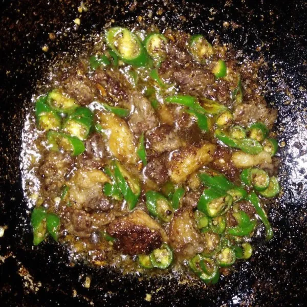 Setelah daging agak kering, masukkan irisan cabe hijau besar dan tumis hingga layu.