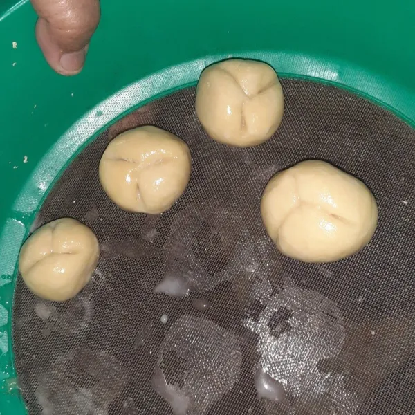 Buat adonan berbentuk bola, lalu belah atasnya, agar roti mekar saat digoreng. Basahi bola-bola adonan dengan air.