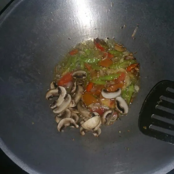 Panaskan 3 sdm minyak, tumis bawang merah, dan bawang putih sampai harum. Masukkan cabai, aduk rata lalu masukkan jamur dan tomat, aduk rata.