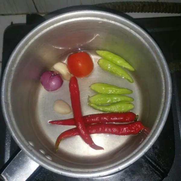 Rebus bawang merah, bawang putih, cabe merah, cabe rawit, dan tomat. Rebus sampai layu, tiriskan.