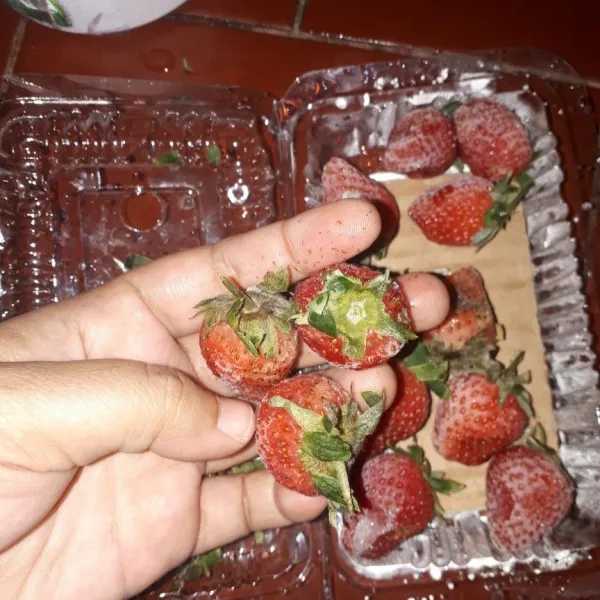 Bersihkan strawberry beku, pisahkan dari daunnya dan cuci bersih.
