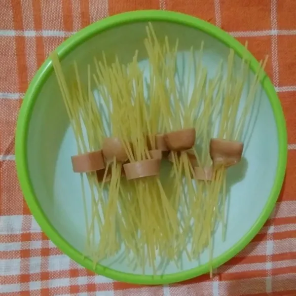 Tusuk spaghetti pada sosis.